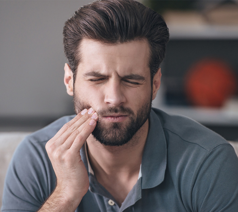 Man holding cheek with tooth pain